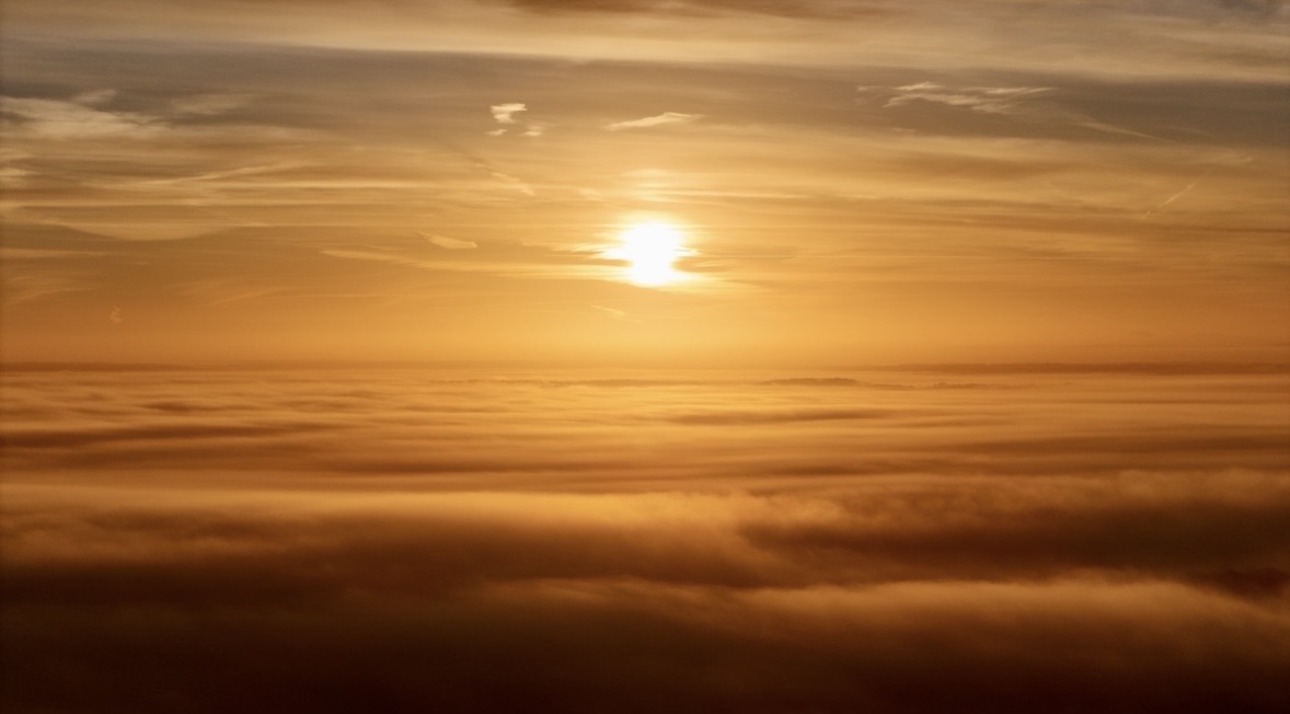 Warm golden sunlight breaking across a dramatic layer of clouds